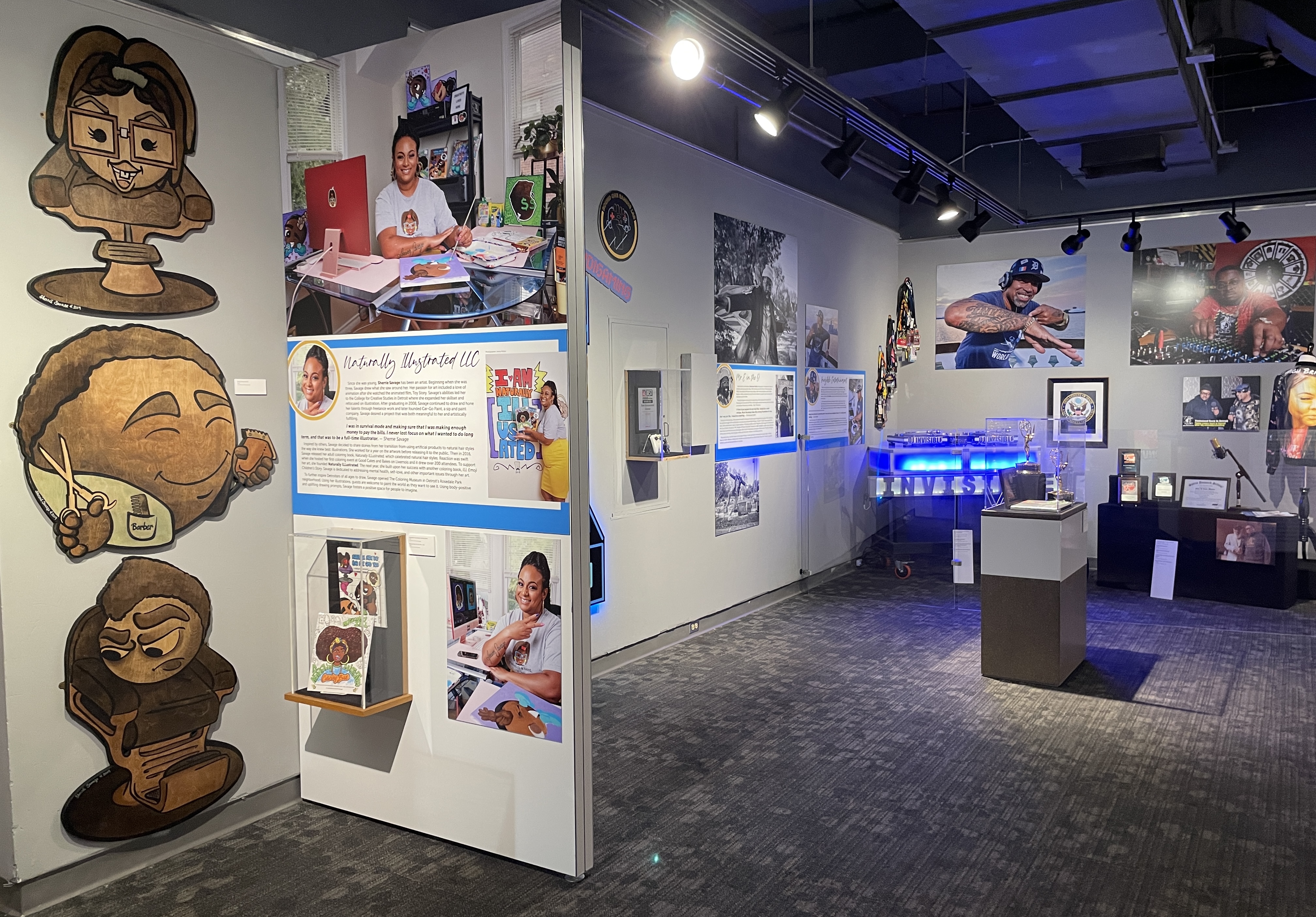Exhibit room with cartoon murals, informational panels, and art displays under spotlights in a modern setting.