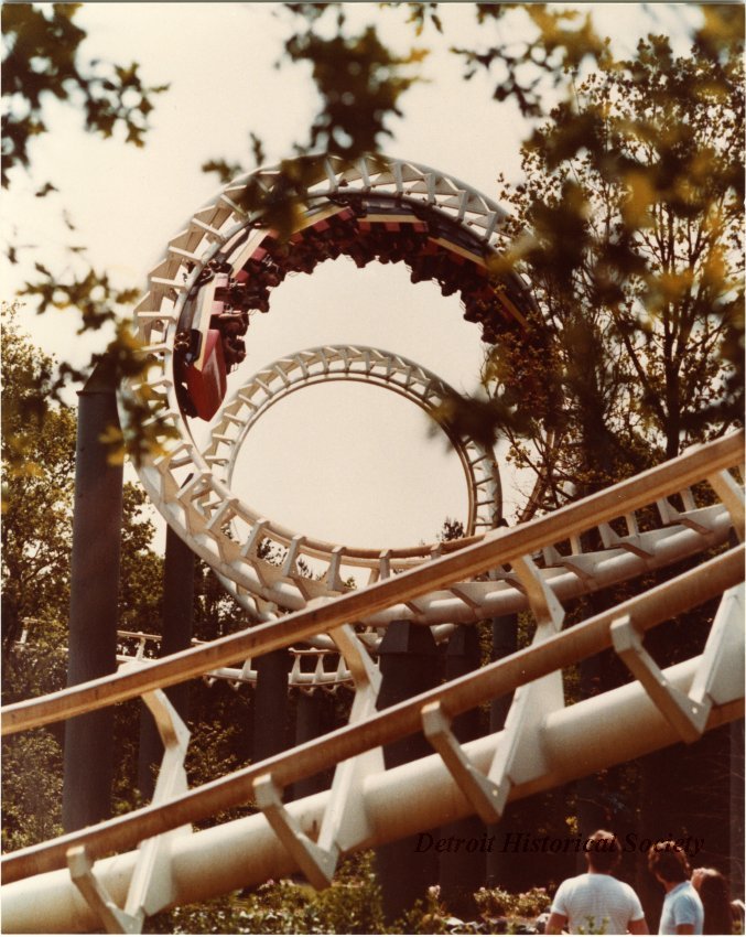 Color photographic print of the Corkscrew on Boblo Island. Color photographic print taken of the double corkscrew portion of Boblo Island's roller coaster, the Screamer. The ride's train is inverted in the second corkscrew. Several people watch from the ground in the lower right corner.