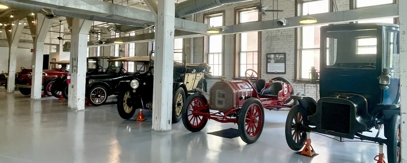 Vintage cars displayed in a spacious, well-lit museum with large windows and industrial decor.