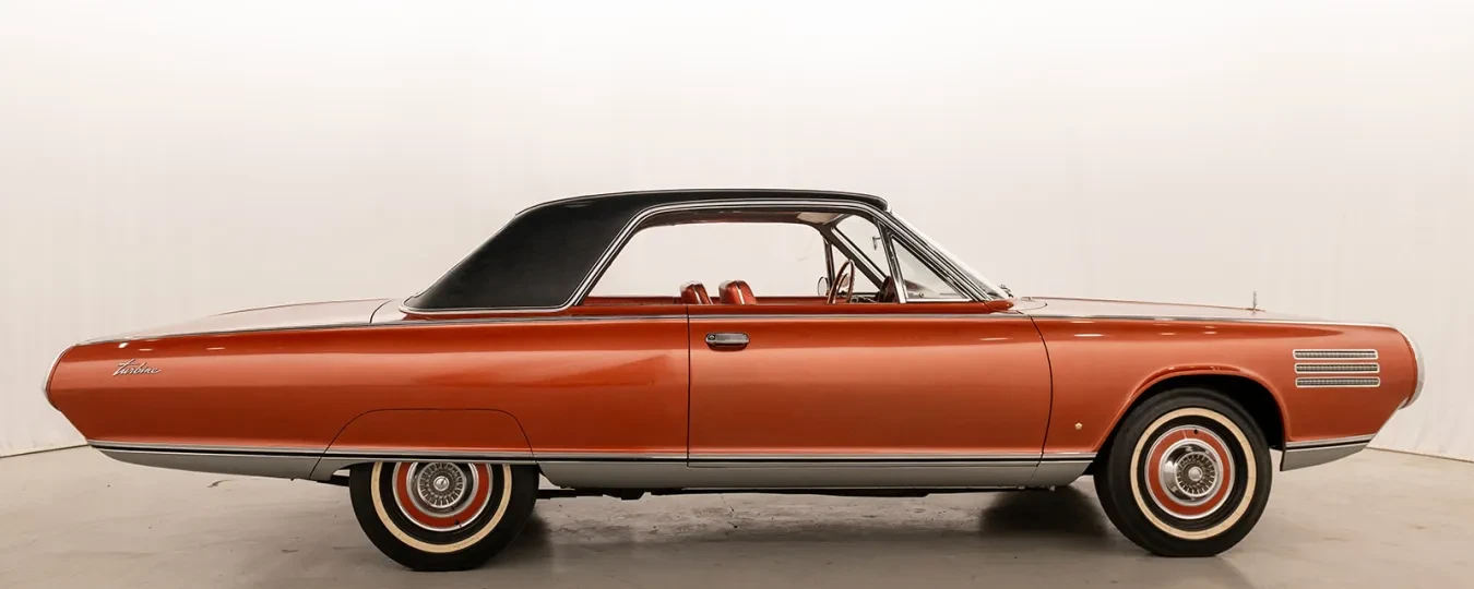 Classic orange car with a black roof in a studio setting.