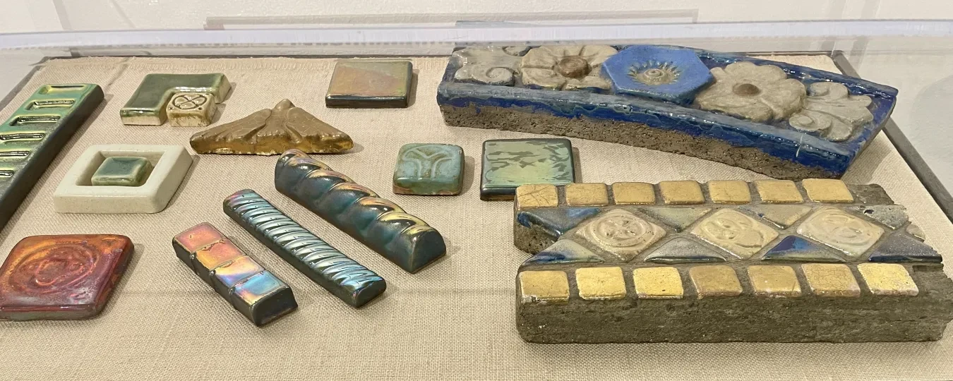 Decorative ceramic tiles and borders displayed in a glass case.