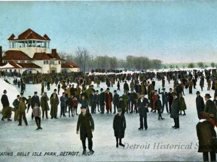 colorized photo of ice skaters on the frozen Detroit river with a building and trees in the distance. Photo taken in the early 1900s at Belle Isle.
