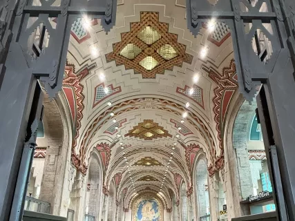 Ornate cathedral interior with arched ceiling, decorative patterns, and central aisle flanked by columns.