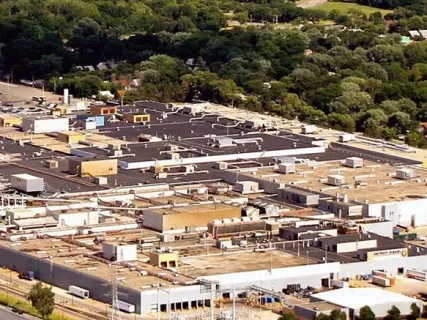 Aerial view of a large industrial complex surrounded by trees and suburban homes.