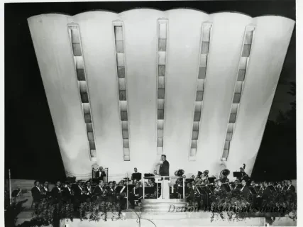 Orchestra performing on stage with a large, dramatic backdrop.