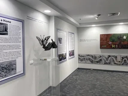 Museum gallery with informational panels, a sculpture, and a colorful mural on the wall.