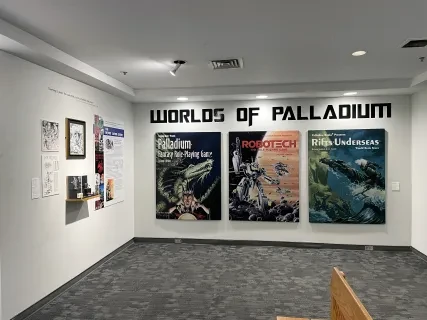 Exhibition wall with "Worlds of Palladium" posters, showcasing sci-fi themes and artwork.
