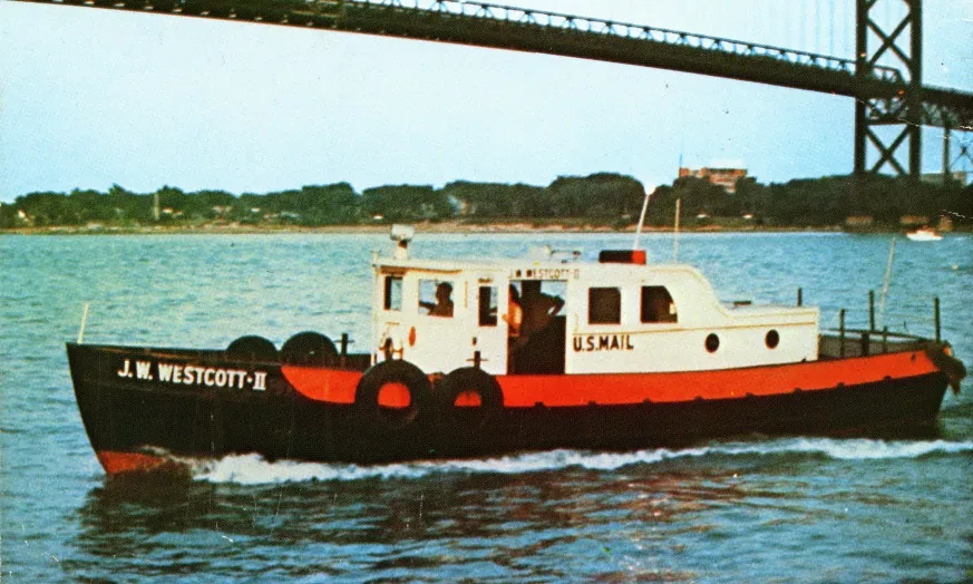 Small boat on river under a bridge, white and red with black tires as bumpers, trees in the background.