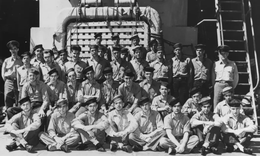 Group of military personnel in uniforms posing in front of a building and stairs, black and white photograph.