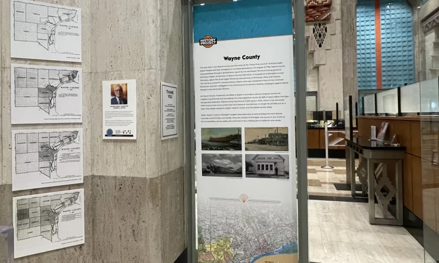 Display panel in a hallway with maps and text about Wayne County. Contains historical photos and maps on the left wall.
