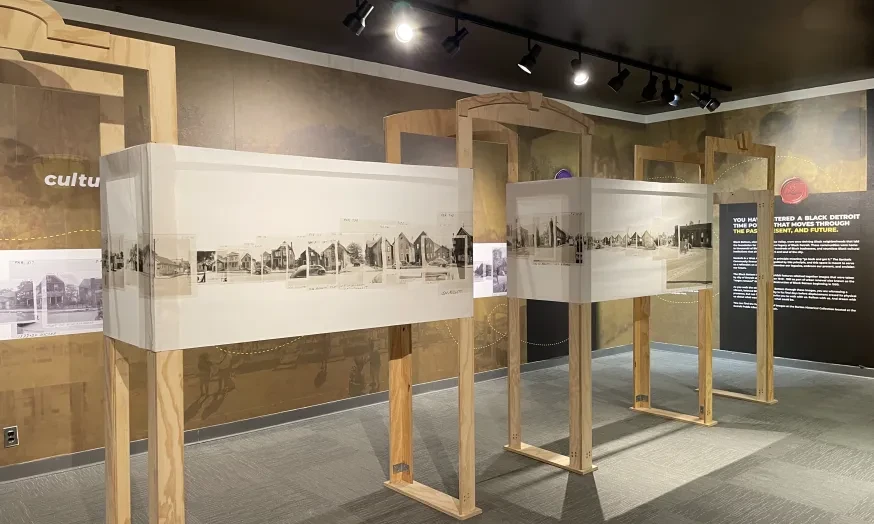 Exhibit room with historical panoramic photos on wooden frames, neutral tones.