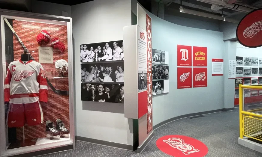 Hockey exhibit with vintage uniforms, photos, and team logos in a museum setting.
