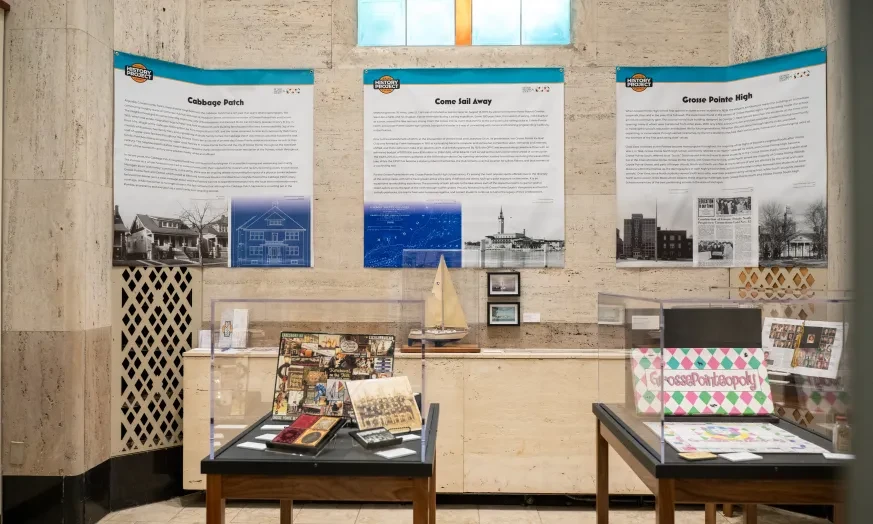 Exhibit room with historical posters on walls, small ship model, and assorted memorabilia on tables.