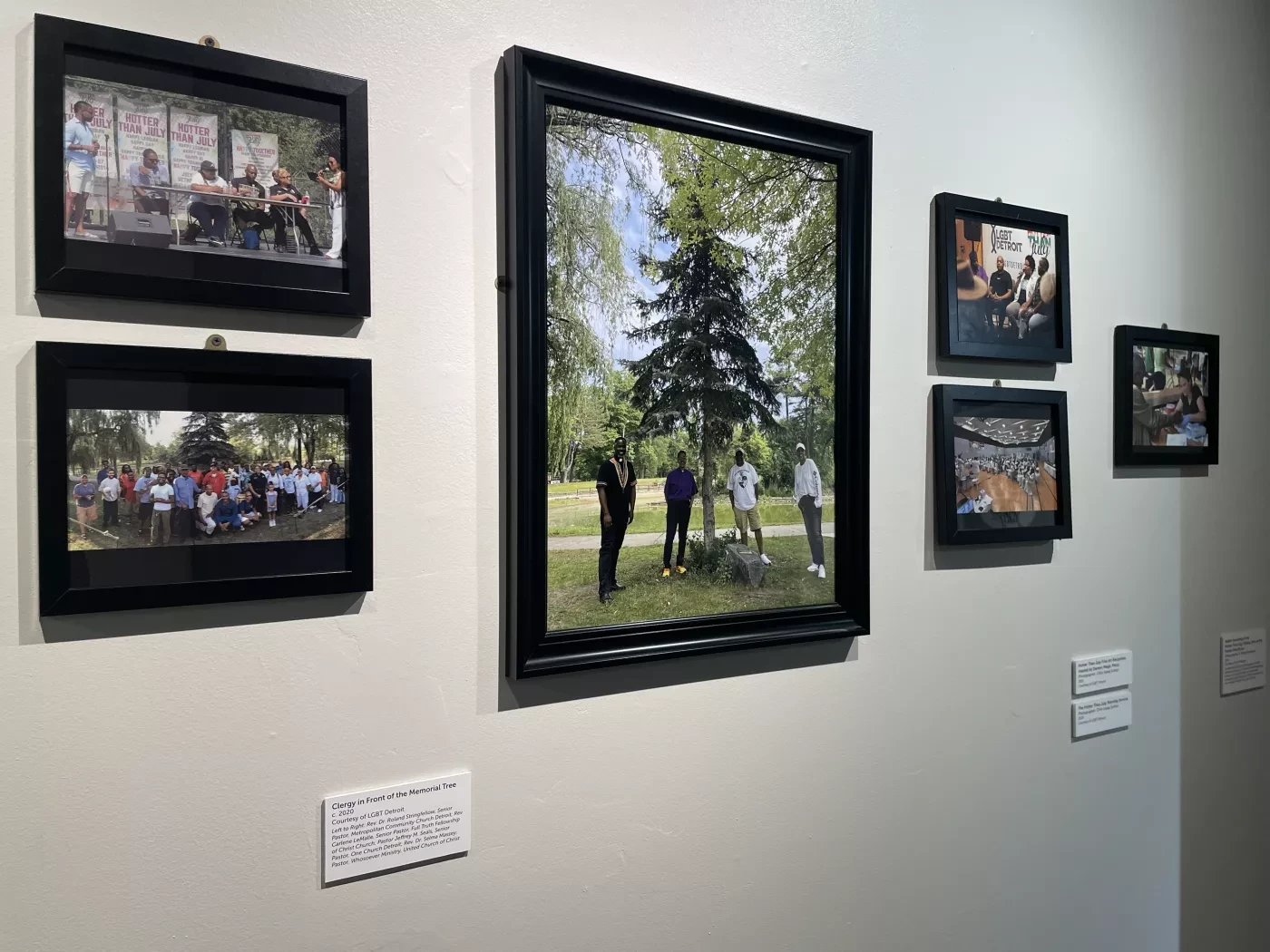 Framed photographs on a gallery wall show various outdoor scenes and group activities.