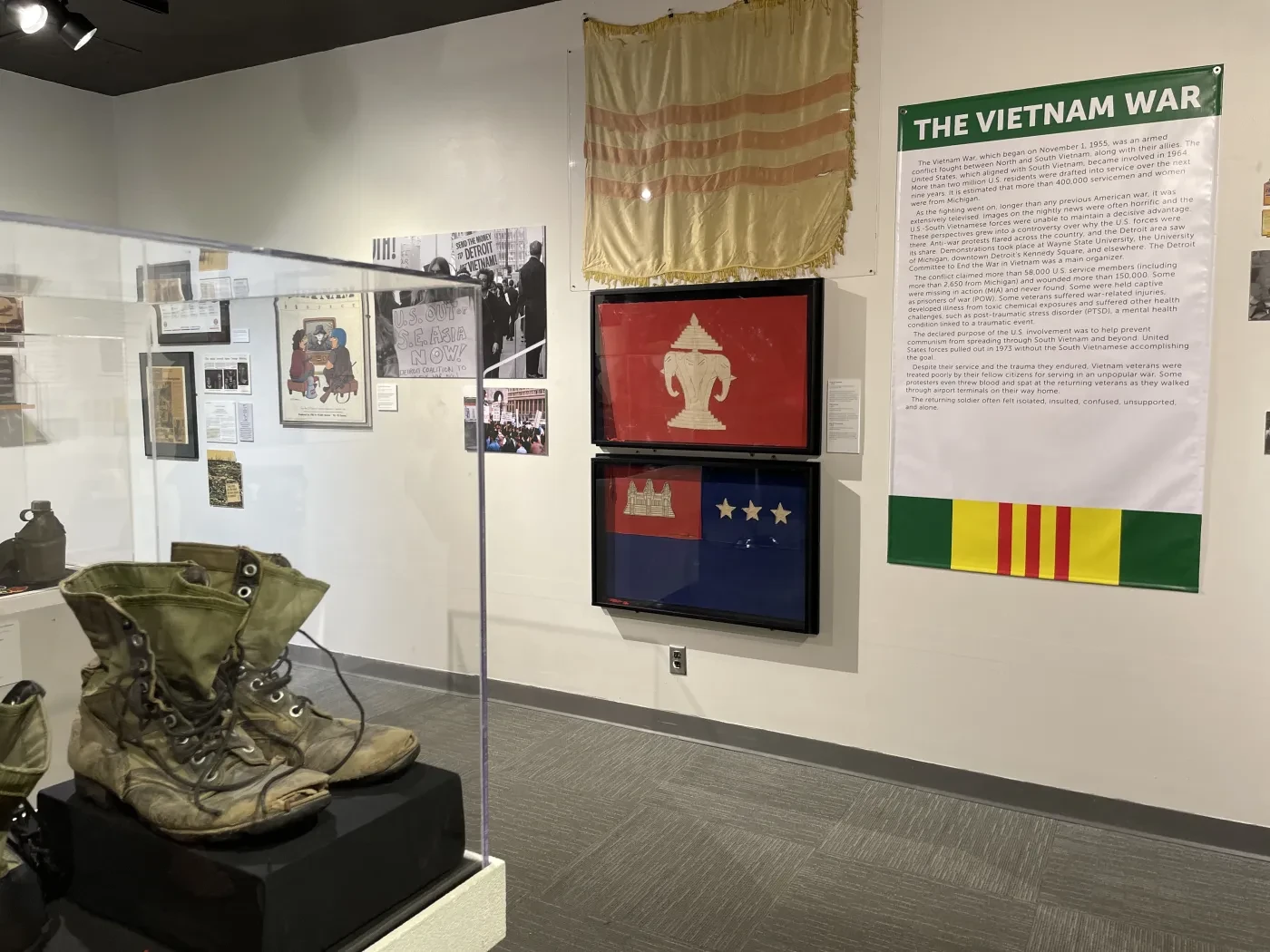 Museum exhibit on the Vietnam War featuring old boots, flags, photos, and informational text on the wall.