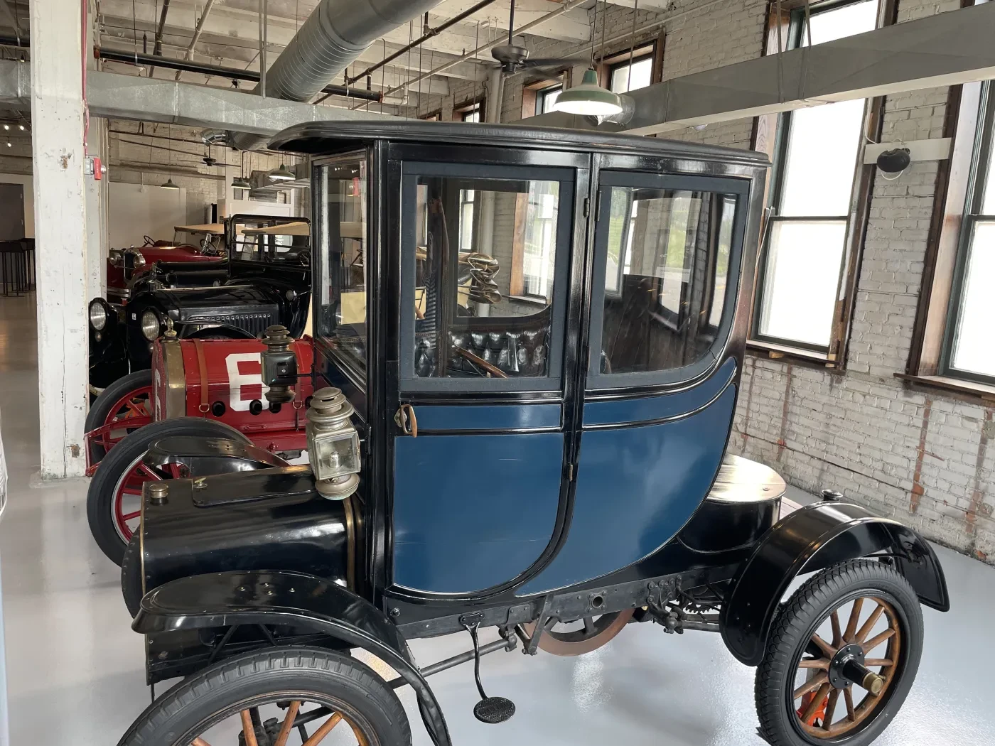 Antique blue car with wooden wheels in a vintage car showroom.