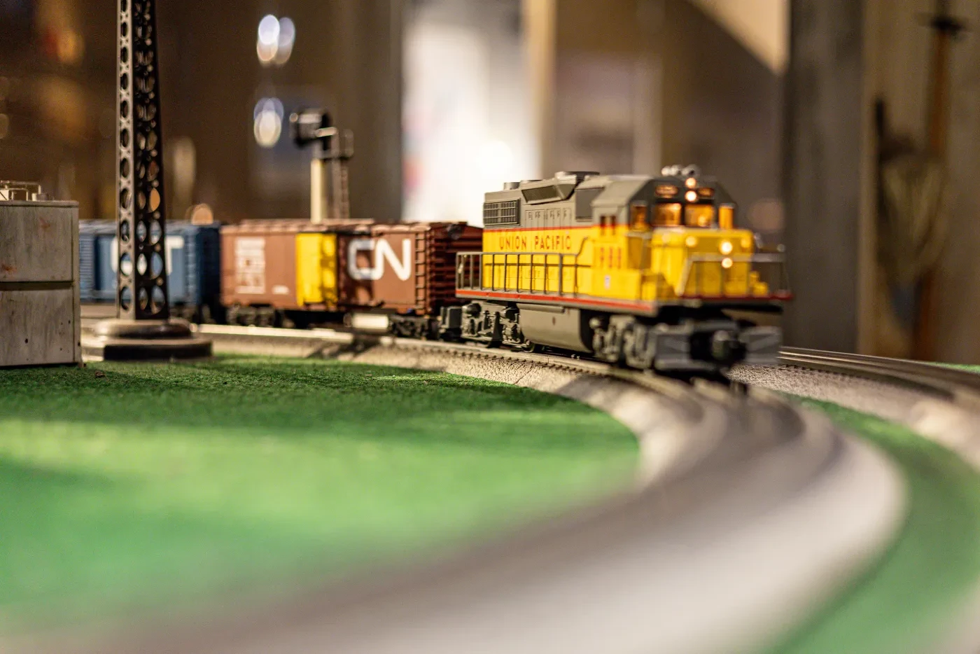 Model train set with a yellow locomotive on a curved track, surrounded by boxcars.