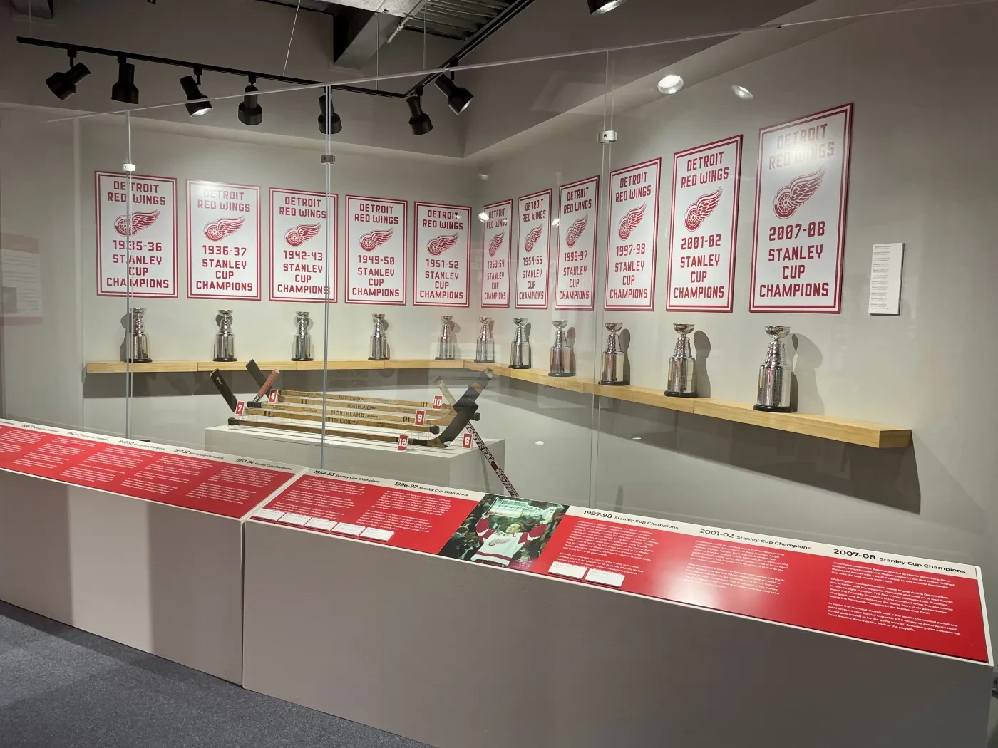Trophies displayed on shelves with championship banners above in a museum setting.