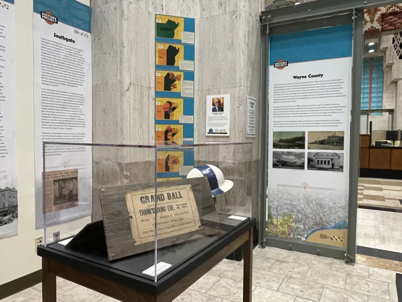 Exhibit room with display case holding signs and hats, surrounded by informative panels on walls.