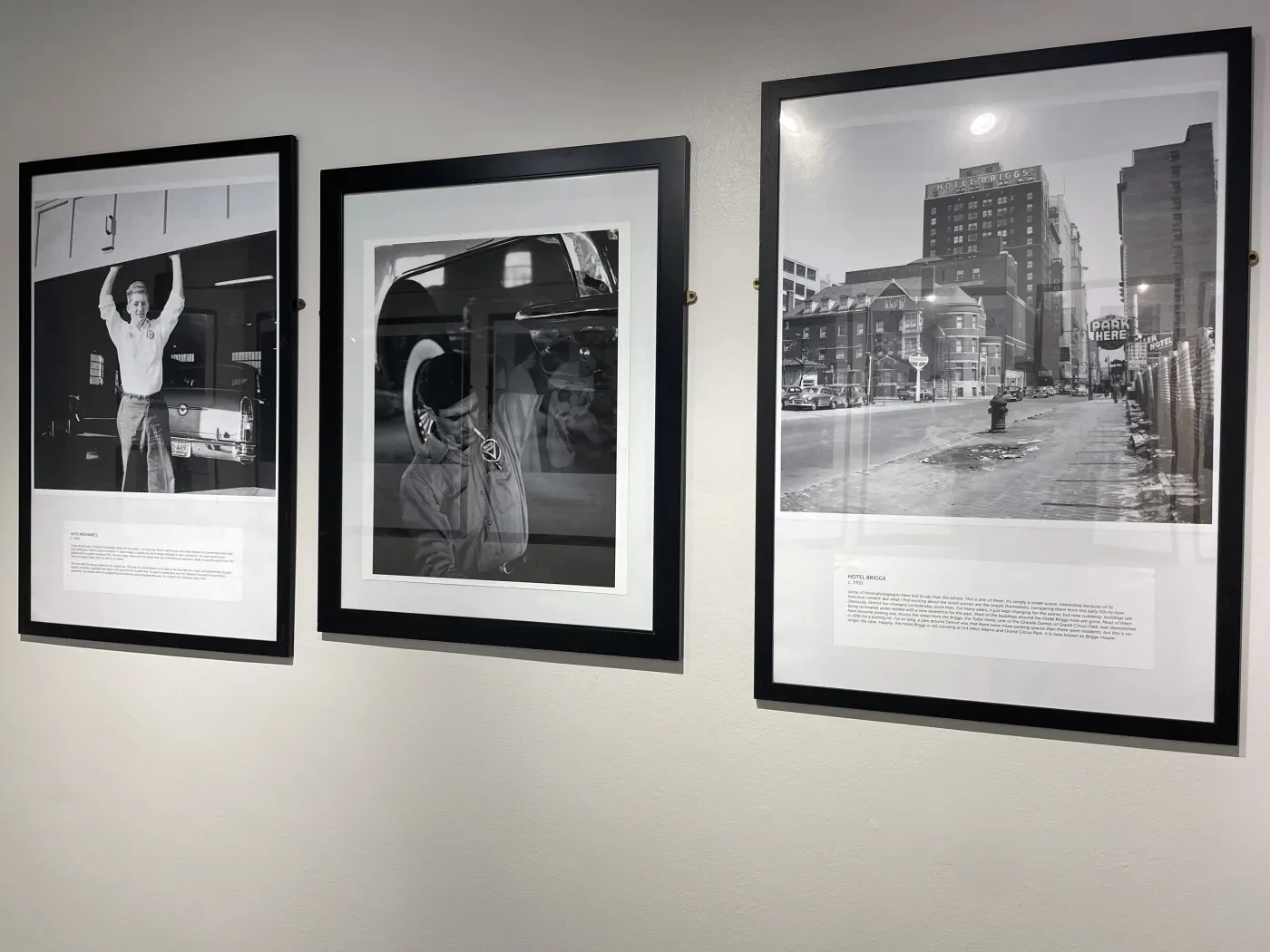 Three framed black and white photographs on a wall, depicting urban scenes and figures.