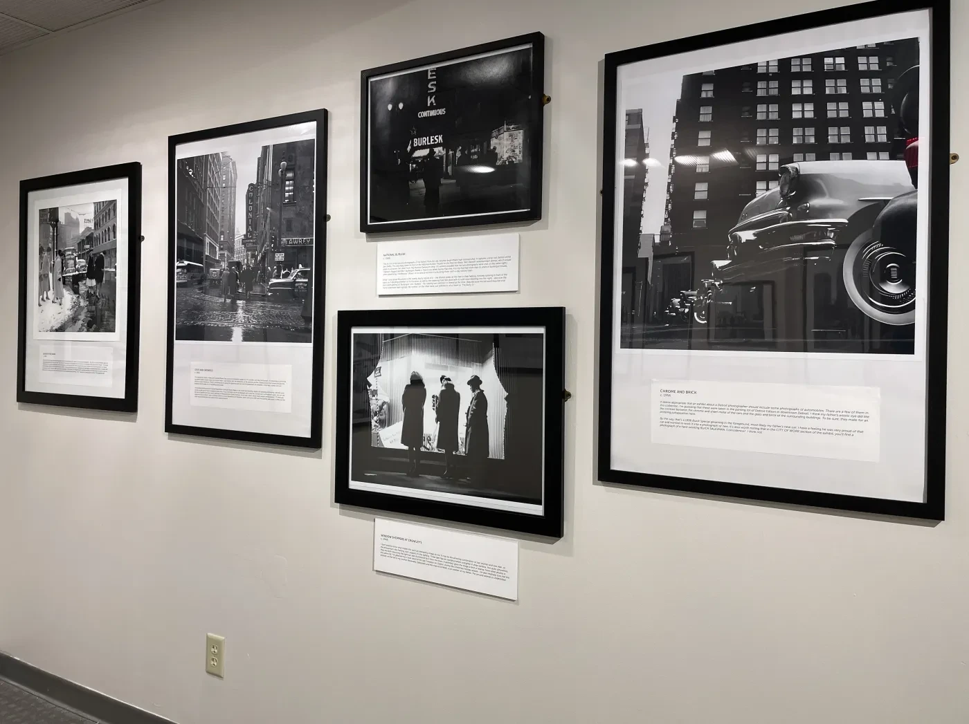 Black and white framed photographs on a gallery wall depicting city scenes and people.