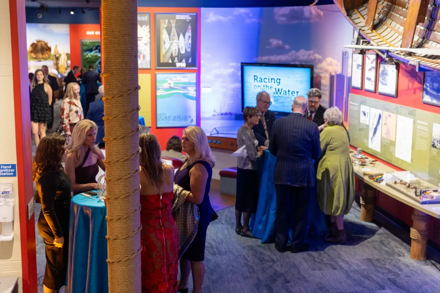 Guests socializing at a colorful exhibit event, with various displays and posters on the walls.