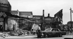 A Detroit police officer stands in front of a destroyed store. From the Detroit Historical Society Collection.